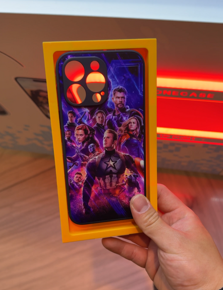 Custom phone case featuring colourful superhero artwork held in front of a SnapShell vending machine
